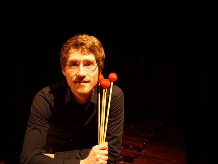 Porträt eines jungen Mannes mit Instrumenten vor einem dunklen Hintergrund